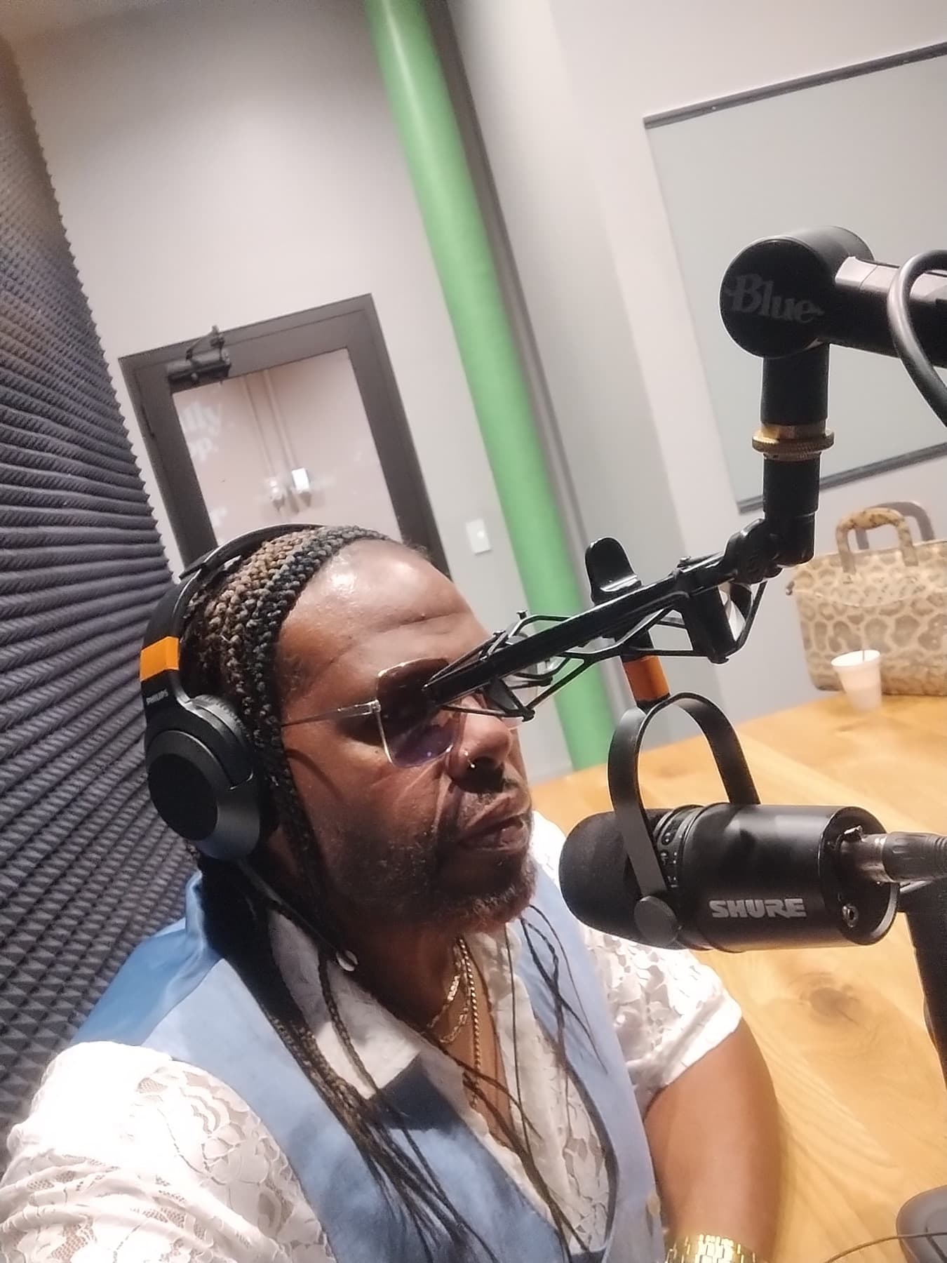 Dr. Fain in a podcast booth wearing headphones and speaking into a microphone