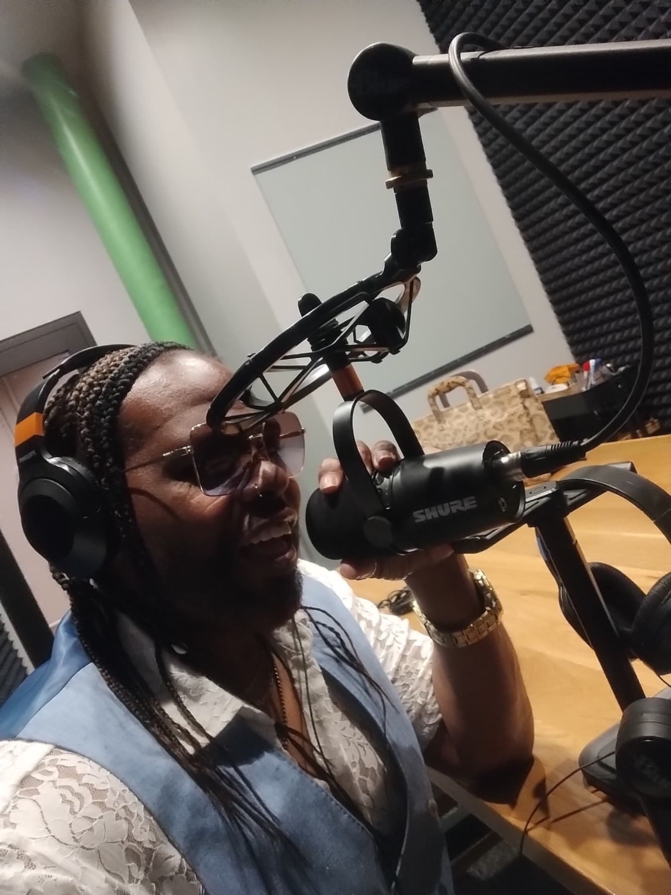 Close photo of Dr. Fain smiling at a podcast microphone in the recording booth